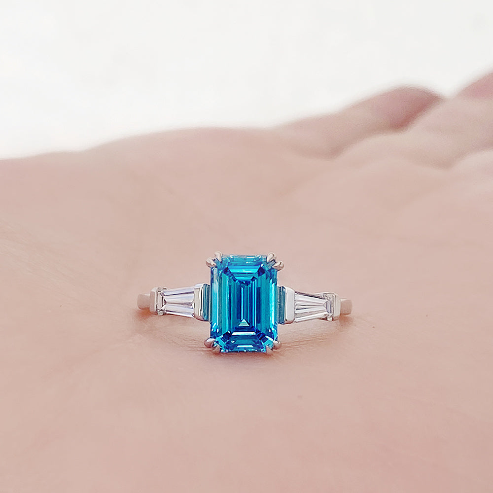 Carmen, a Blue Emerald cut Trilogy Ring