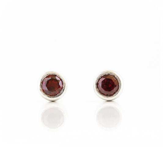 round cut red garnet stud earrings in a sterling silver bezel tube setting