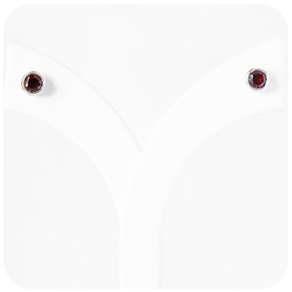 round cut red garnet stud earrings in a sterling silver bezel tube setting