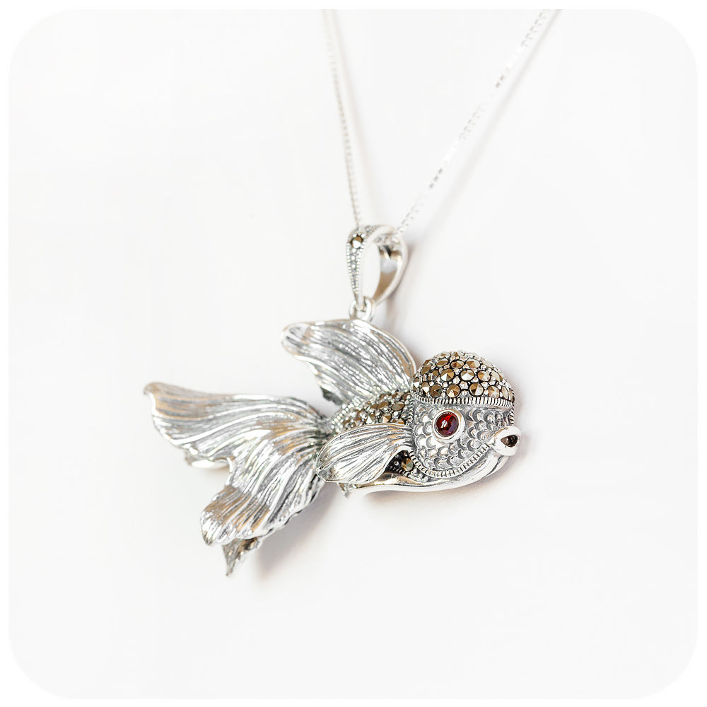 artistic and lifelike goldfish pendant made of sterling silver with beautiful detail and a garnet gemstone in the eye