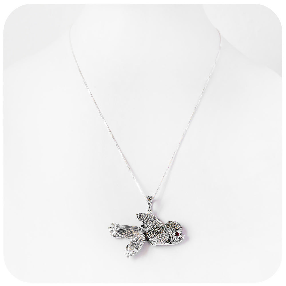 artistic and lifelike goldfish pendant made of sterling silver with beautiful detail and a garnet gemstone in the eye
