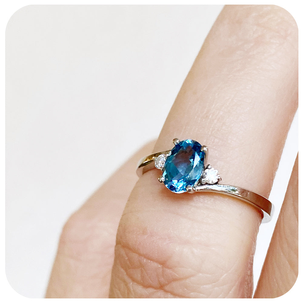 Oval cut Swiss Blue Topaz and Moissanite Trilogy Ring with a Twist