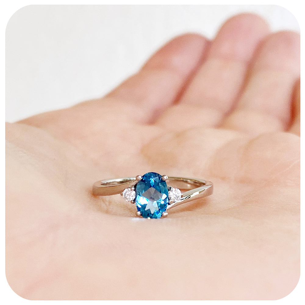 Oval cut Swiss Blue Topaz and Moissanite Trilogy Ring with a Twist