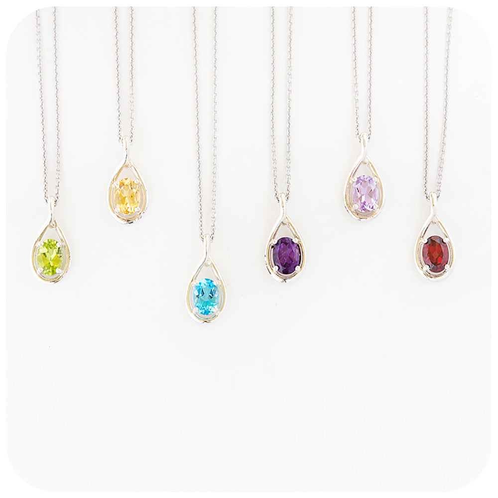 a collection of oval cut birthstone pendants with peridot, citrine, topaz, amethyst and garnet