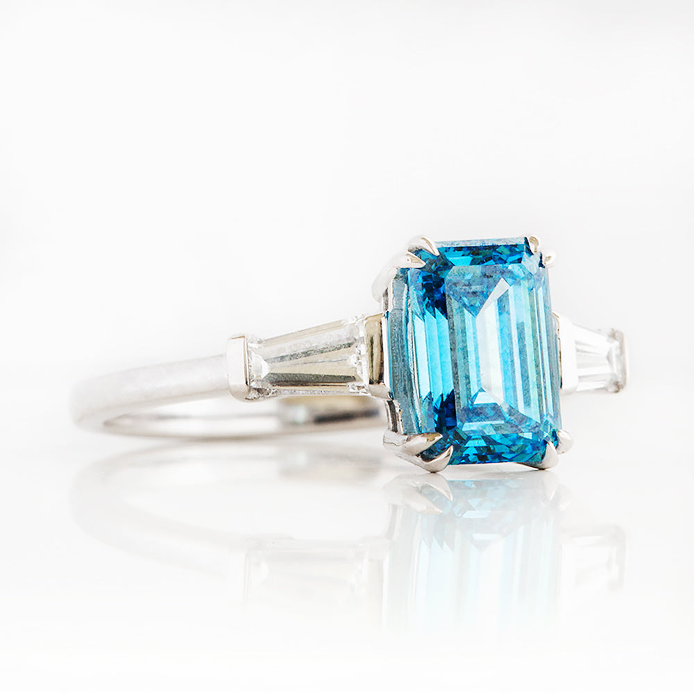 Carmen, a Blue Emerald cut Trilogy Ring