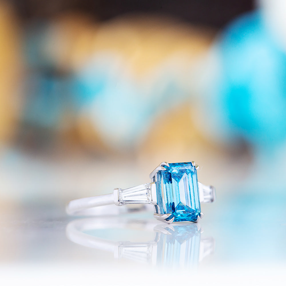 Carmen, a Blue Emerald cut Trilogy Ring
