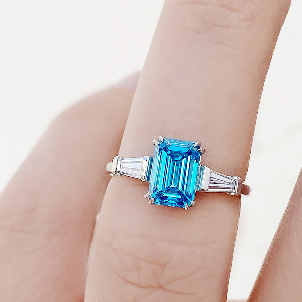 Carmen, a Blue Emerald cut Trilogy Ring