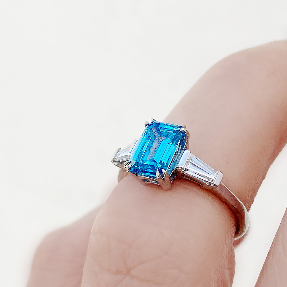 Carmen, a Blue Emerald cut Trilogy Ring