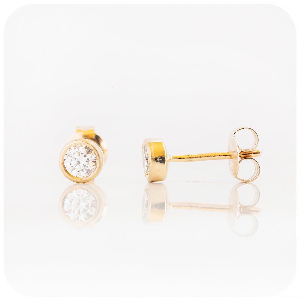 brilliant round cut moissanite stud earrings in a bezel tube yellow gold design - Victoria's Jewellery