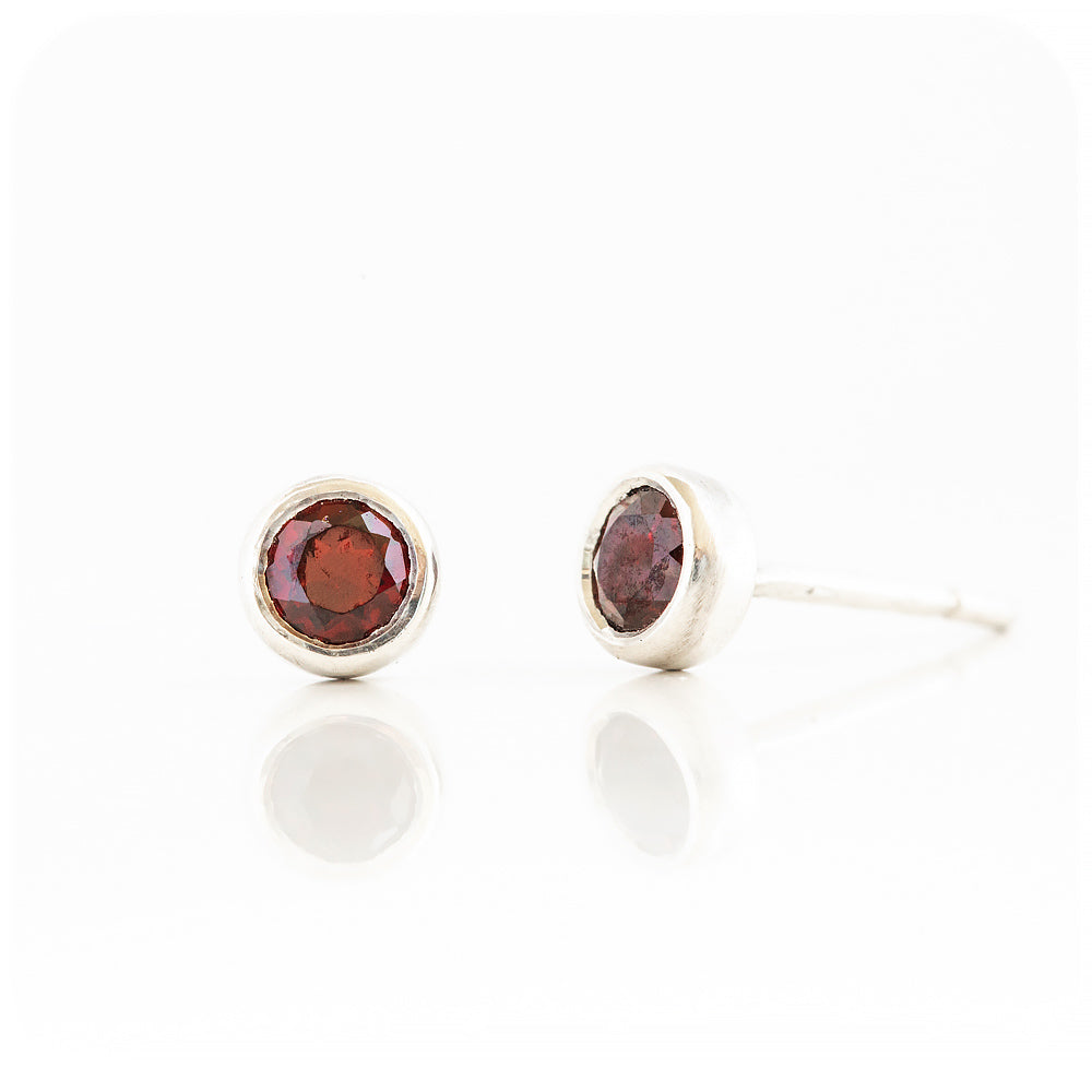 round cut red garnet stud earrings in a sterling silver bezel tube setting