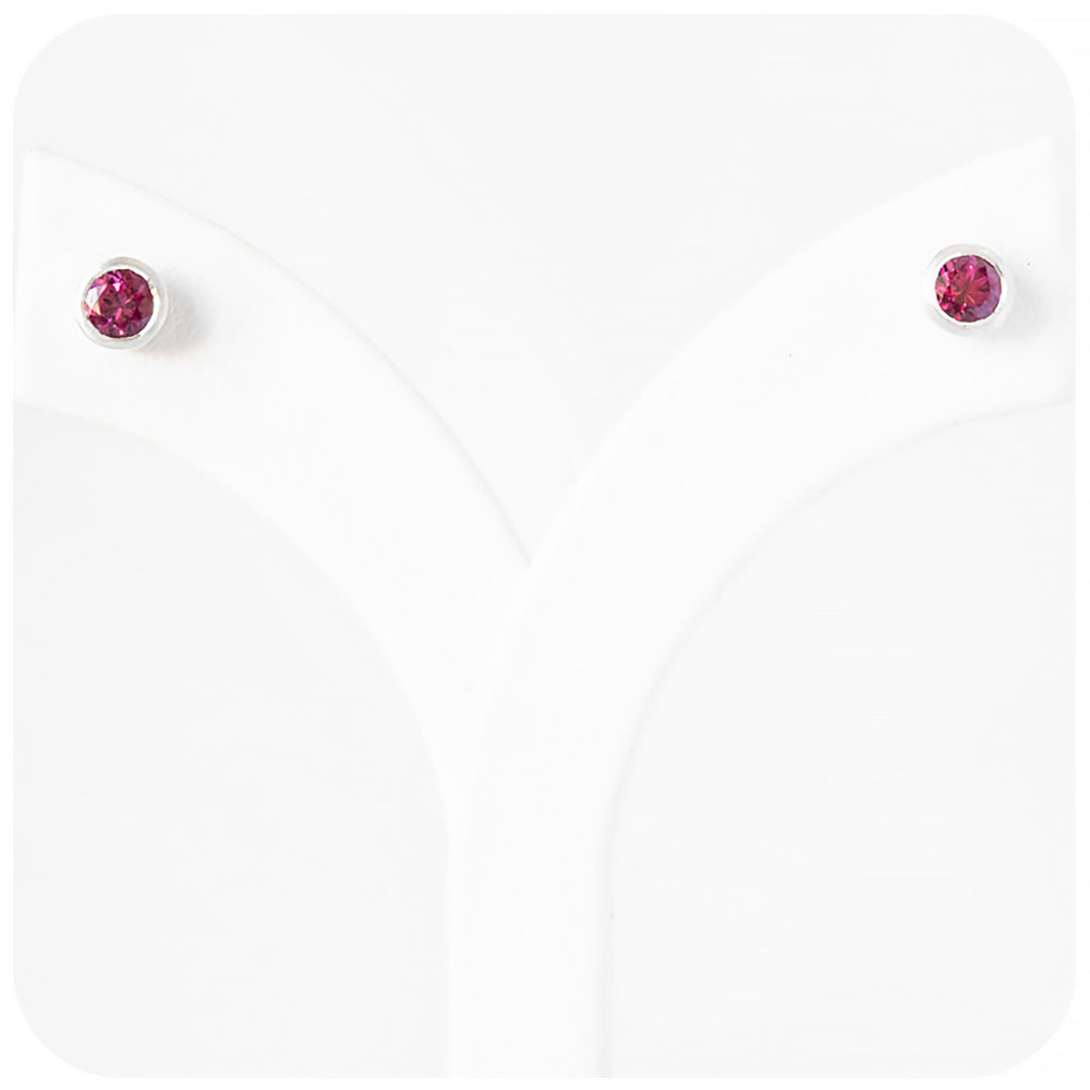 round cut pinkish red rhodolite stud earrings in a sterling silver bezel tube setting