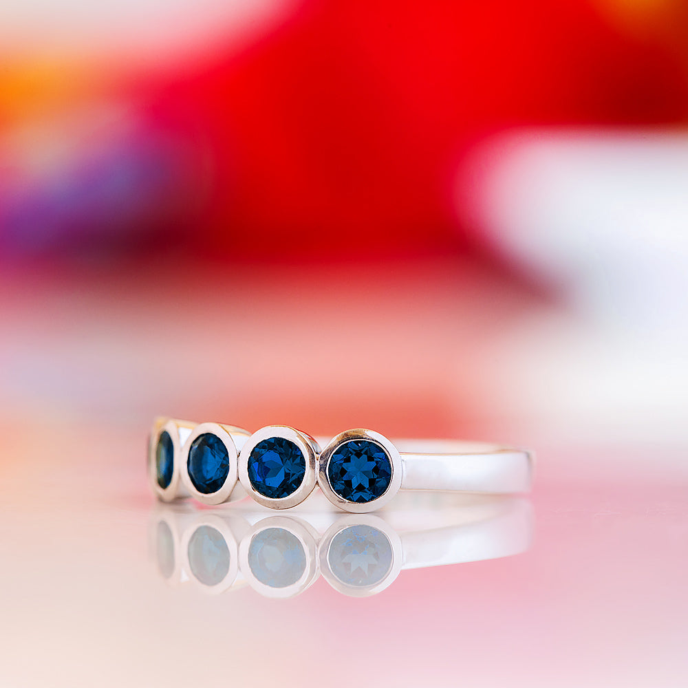 Violet, a Lab Sapphire Bezel Set Half Eternity Ring