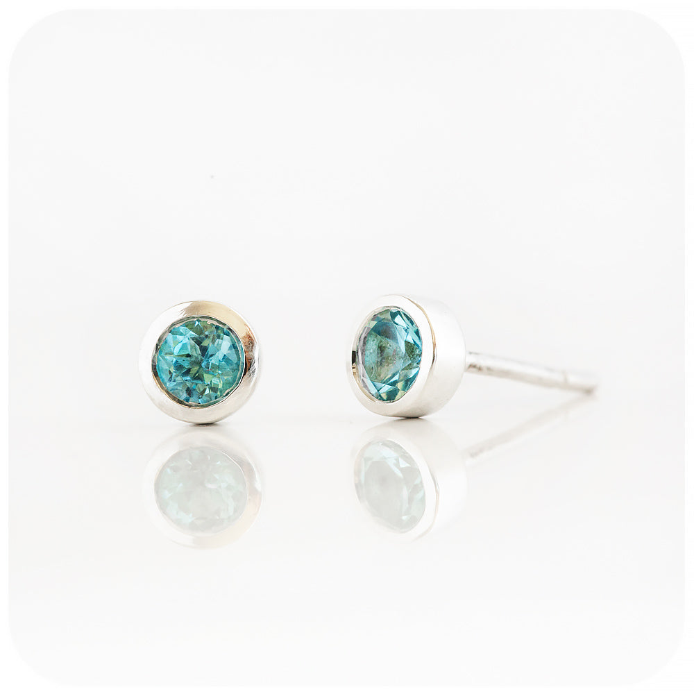 round cut swiss blue topaz stud earrings in a sterling silver bezel tube setting