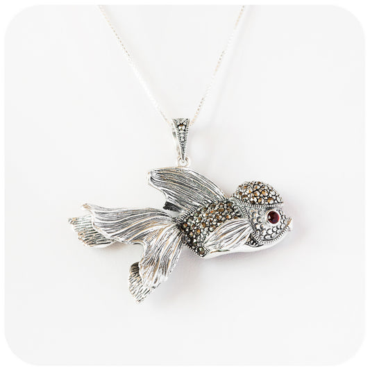 artistic and lifelike goldfish pendant made of sterling silver with beautiful detail and a garnet gemstone in the eye