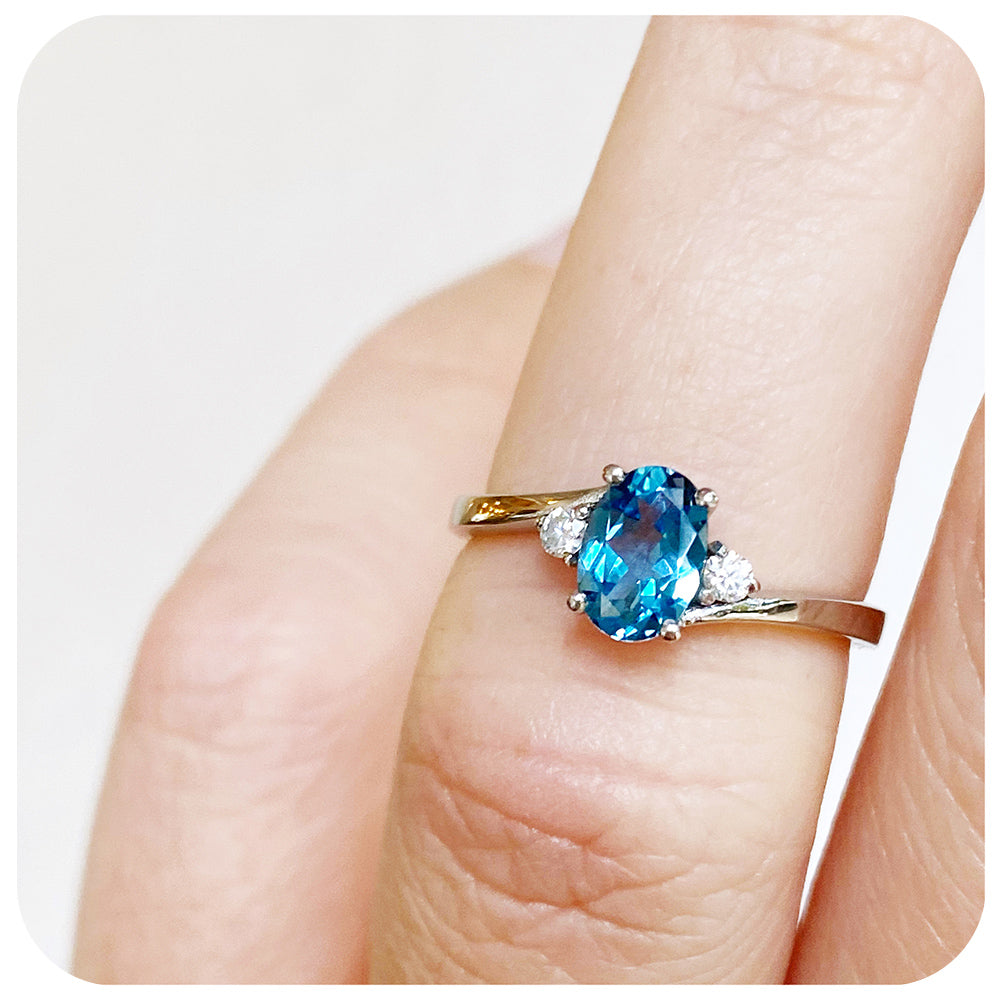 Oval cut Swiss Blue Topaz and Moissanite Trilogy Ring with a Twist